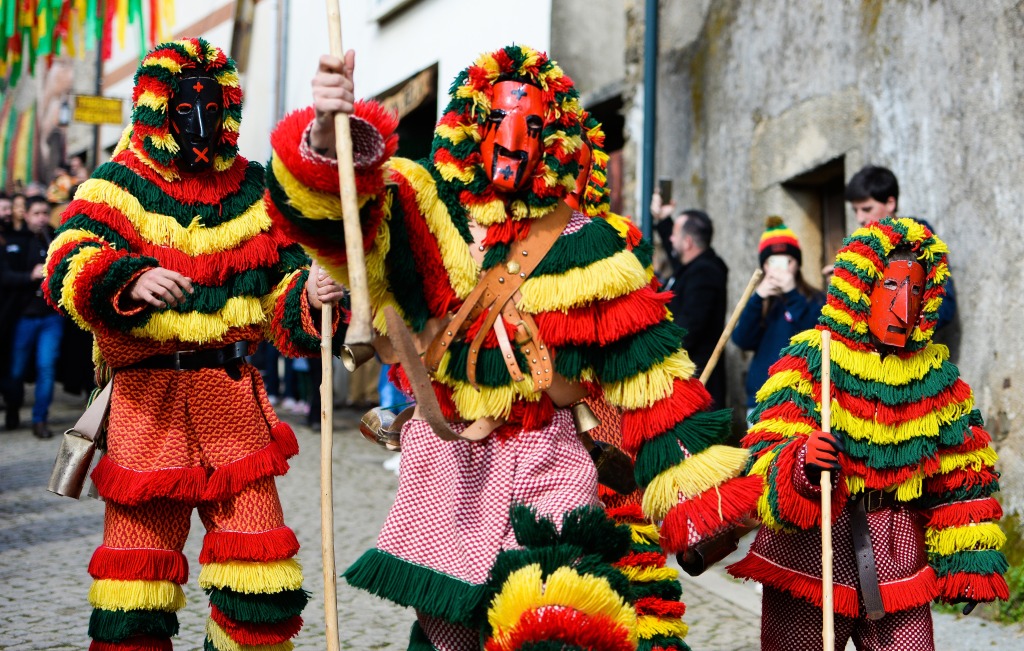 Two adults and a child in Caretos carnival costume of Podence, Portugal