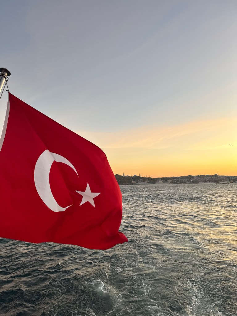 The Turkish flag flying on the back of a boat at sunset