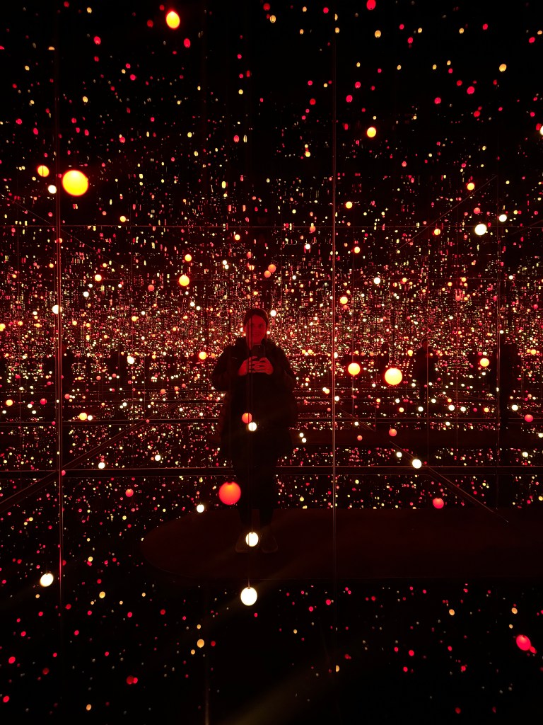 A woman (me) surrounded by coloured lights in a dark room
