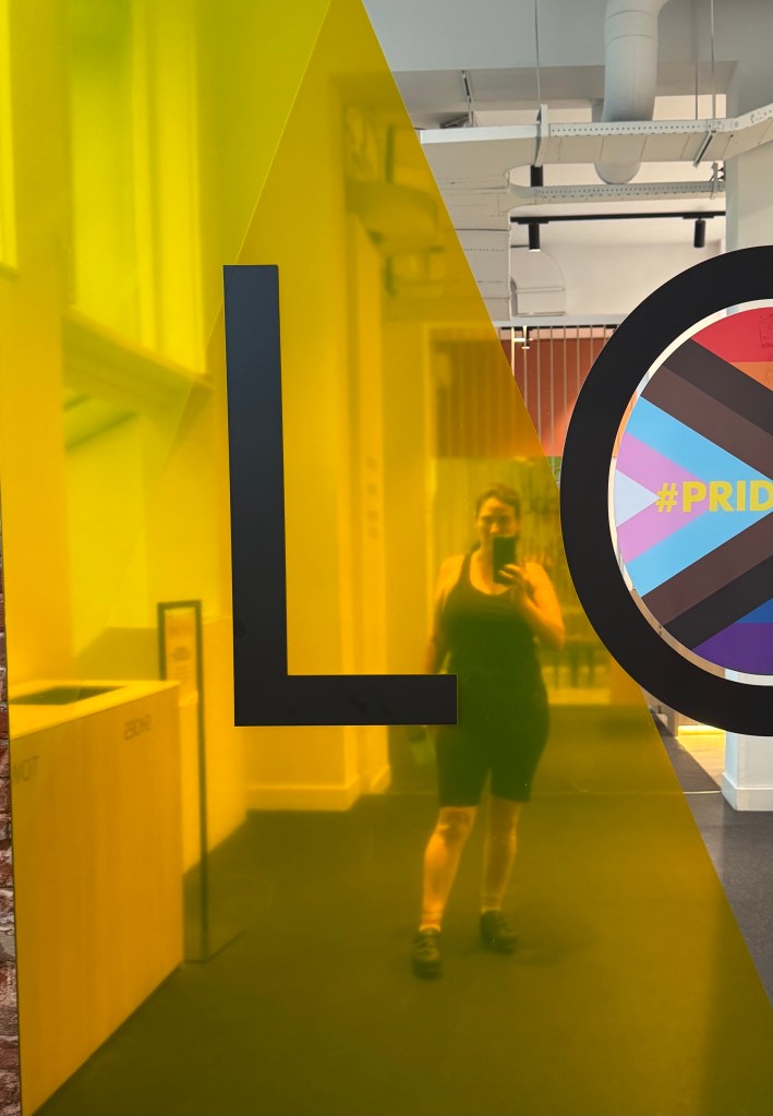 A woman (me) reflected in the mirror at the gym