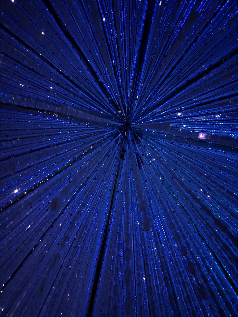 A mesmerizing display of strings adorned with blue lights radiating outward, creating a starburst effect against a dark background.