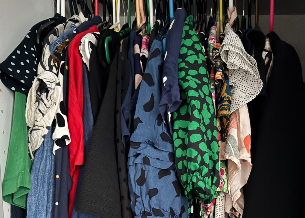 A colorful assortment of clothes hanging on a closet rack, showcasing various patterns and textures.
