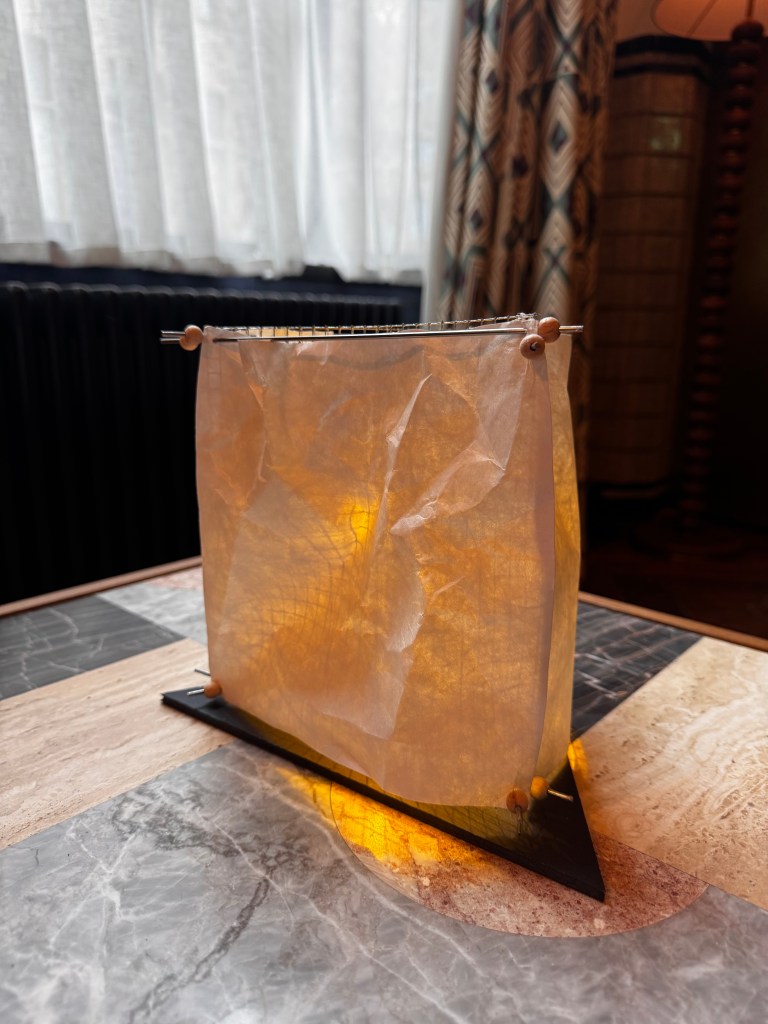 A lit decorative lamp made of crinkled paper, positioned on a textured tabletop with various stone patterns.
